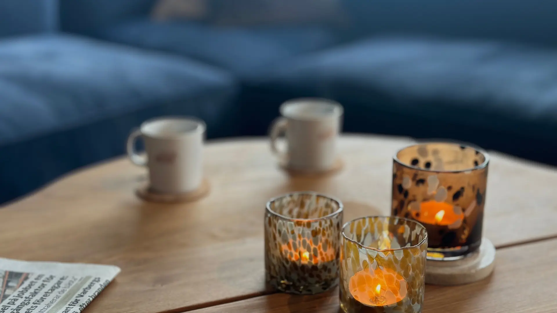 Ett bord i loungen med två ljus och en tidning, skapar en mysig atmosfär för avkoppling och samtal.